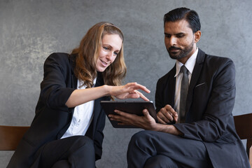 Two Business Professionals Collaborating with Digital Tablet: Workplace Discussion, Teamwork, and Strategic Decision-Making