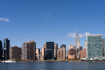 Obraz premium Manhattan skyline featuring iconic skyscrapers and waterfront on a clear day.