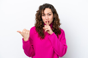 Young caucasian woman isolated on white background pointing to the side and doing silence gesture