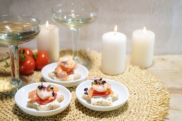 Sandwich snacks in star shape with shrimps, salmon and tomato, champagne drink and candles, appetizer for a holiday party on Christmas or New Year, copy space, selected focus