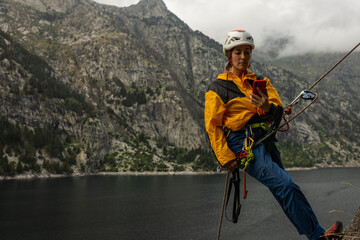 A woman is standing on a mountain with a cell phone in her hand