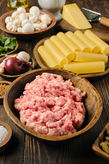 Preparing ingredients for a delicious meat and cannelloni pasta dish on a rustic wooden table