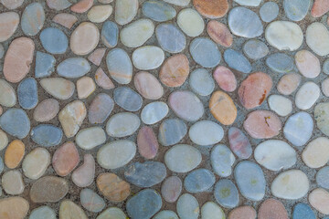 Part of a gray concrete road with multi-colored sea pebbles embedded in it. Abstract background.