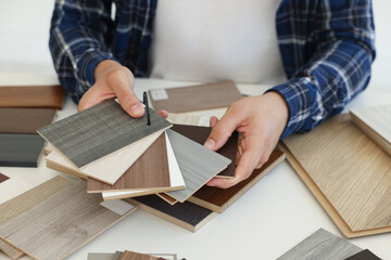 Man choosing wooden flooring among different samples at table, closeup