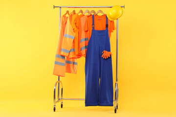 Workers' uniforms on clothing rack against yellow background
