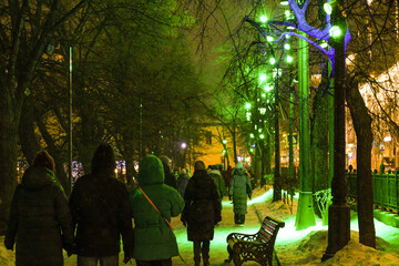 A group of people is walking down a snowy street during the night