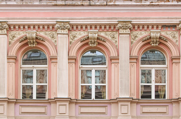 There are three distinct windows located on the side of a white building