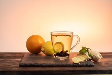 Tea in a transparent mug with a handle. A slice of lemon and mint in a mug. Mint and ginger in tea. Medicinal tea. Bright background.