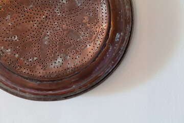 Copper saucepan hanging in kitchen, white wall