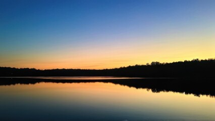 A tranquil lakeside sunset reflecting vibrant colors in the water.