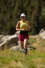 A woman is running in a field with a hat on