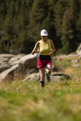 A woman is running in a field with a hat on