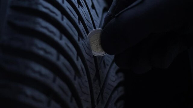 Close-up of the coin in the tire tread. Protector depth check.