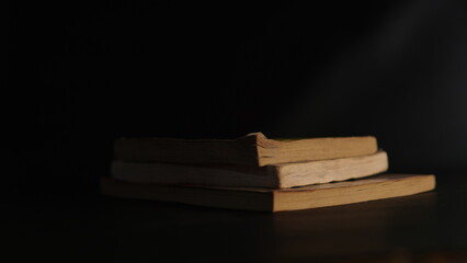 old book. a stack of old books on a black and dark background with a little light shining on the sides. reading old books, magic books, history books, mysteries, Halloween