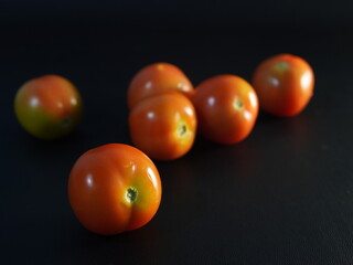 several tomatoes on a black background	