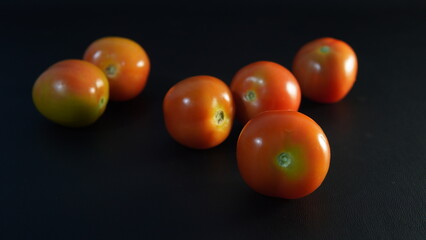 several tomatoes on a black background	