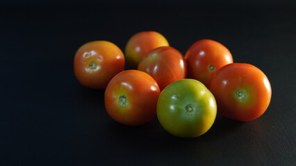 several tomatoes on a black background	