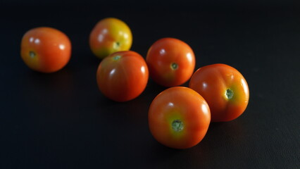 several tomatoes on a black background