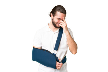 Young handsome man with broken arm and wearing a sling over isolated chroma key background laughing