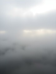 Fototapeta premium A soft, overcast sky with rolling fog moving across the landscape, creating a mysterious, dreamy atmosphere with light breaking through in soft beams