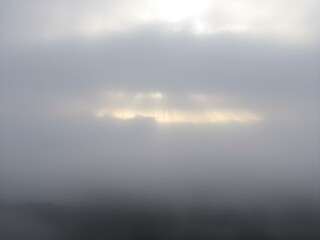 Fototapeta premium A soft, overcast sky with rolling fog moving across the landscape, creating a mysterious, dreamy atmosphere with light breaking through in soft beams