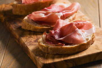 simple bruschetta with prosciutto on wood board