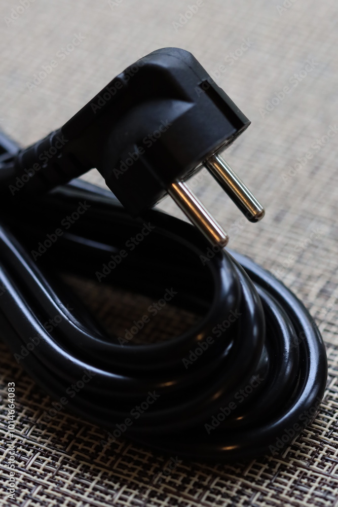 Poster a close-up shot of a black power cord lying on a table.