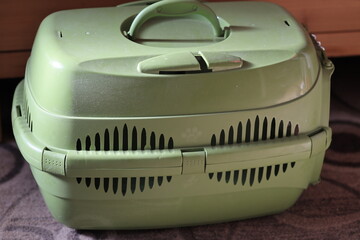 A small green suitcase sits on a colorful carpet.
