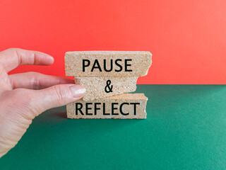 Concept words Pause and Reflect on brick blocks. Beautiful red background, green table. Businessman hand. Business and Pause and Reflect concept.