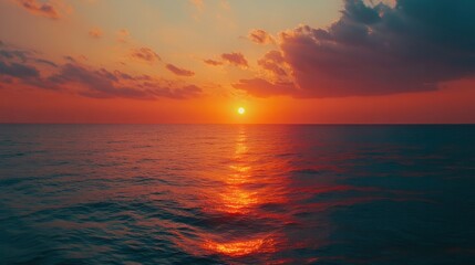 Sunset over the ocean, with vibrant colors reflecting off the calm waves and distant horizon