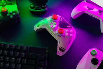 gamer work space concept, top view a gaming gear, mouse, keyboard, game controller, headset, in ear headphone and mouse pad with rgb color on black table background.