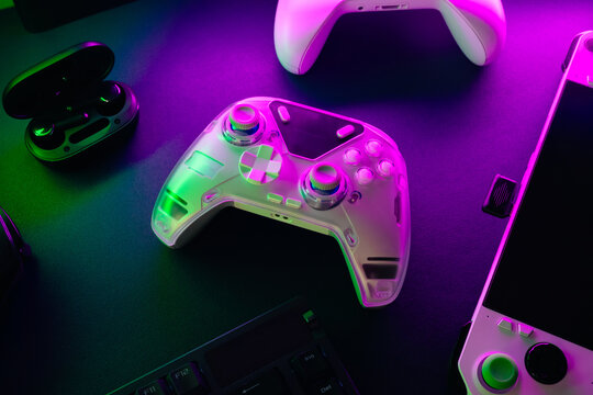 gamer work space concept, top view a gaming gear, mouse, keyboard, game controller, headset, in ear headphone and mouse pad with rgb color on black table background.