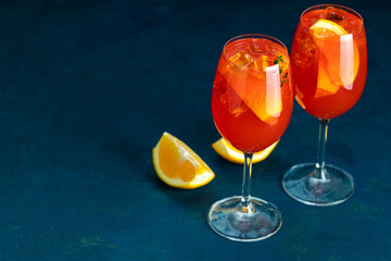 Two glasses of aperol spritz cocktail standing on blue table background
