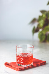 Crystal glass standing on red napkin containing red cocktail