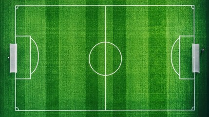 Aerial view of a green soccer field with white lines, empty except for a few players training in the distance, captured from directly overhead by a drone