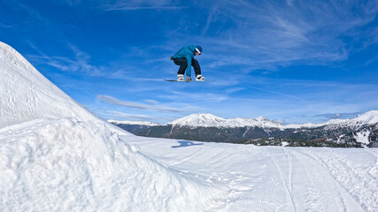 LOW ANGLE: Young male snowboarder rides off a kicker and does a cool grab trick. High-flying...