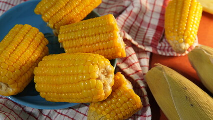 several pieces of boiled corn on a blue plate on the table. flat lay. theme of healthy eating and...