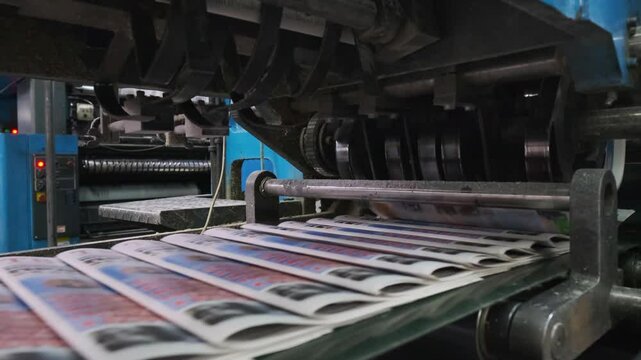 Close-up of printing house machinery in operation, showcasing the process of printing and sorting newspapers with advanced equipment.