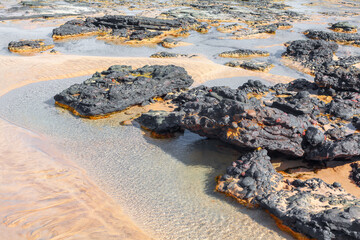 Rocky coastline and sandy beach. Picturesque beach with scattered rocks and clear water