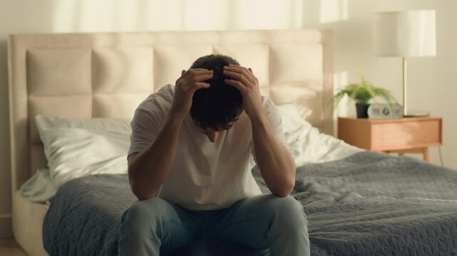 Unhappy Caucasian European man holding head problem crisis breakup male guy bedroom credit debt serious trouble hopelessness depressed grief despair difficulty disappointment sadness emotional stress