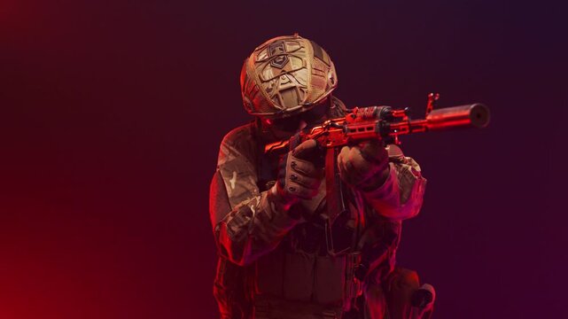 A man in a tactical military uniform with a weapon. Filmed in the studio. Explosions, smoke and flashing blue and red lights. Defense, attack and military action concept