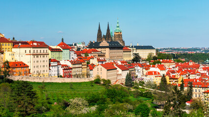 Panoramic view of Prague featuring historic castle and vibrant rooftops on a sunny day in summer....