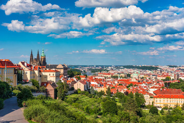 Fototapeta premium View of Prague featuring historic castle and vibrant rooftops on a sunny day in summer. Aerial view of Prague, Charles Bridge over Vltava river in Prague, Czechia. Old Town of Prague, Czech Republic.