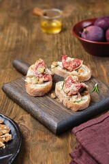 Bruschetta, open sandwich with baked figs, blue cheese and walnuts on a wooden board. Recipes figs.