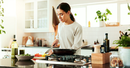 Cooking, woman and kitchen knife at stove with lunch, healthy food and relax in home with smile at...