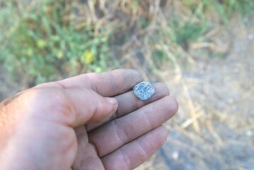 Treasure with a metal detector. A treasure hunter digs up found objects, coins, antiques, shows them on camera and explains their possible value or history.