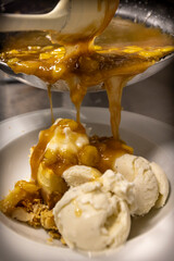 Cheese cake, bananas, caramel dessert. Making dessert behind the scenes. Vanilla Ice cream, whip cream topped on cheese cake, banana sauce topping with caramel on top. 