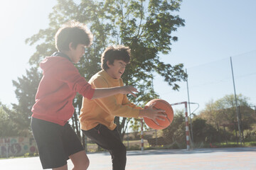 Boys playing basketball outdoors on a sunny day