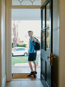 Young boy waving his hand goodbye at the doorway.