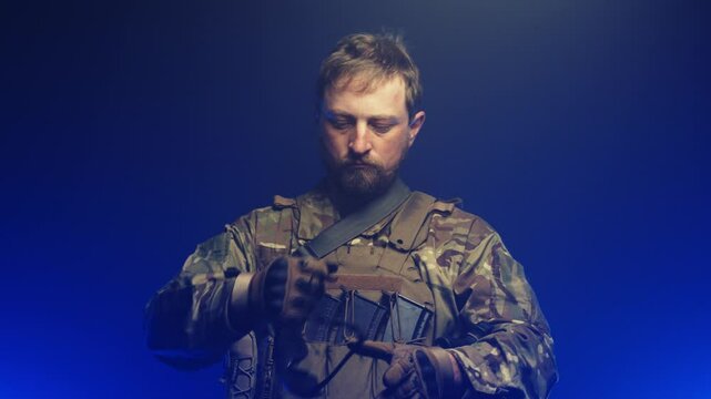 A military man on a blue background in smoke puts on military ammunition. Start of war and preparation concept